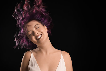 Portrait of happy young woman with unusual hair on black backgroundの写真素材