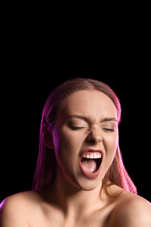 Toned portrait of emotional young woman on black backgroundの写真素材
