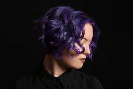 Beautiful young woman with violet hair on black background. Very Peri - color of year 2022の写真素材