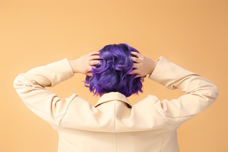 Beautiful young woman with violet hair on color background, back view. Very Peri - color of year 2022の写真素材
