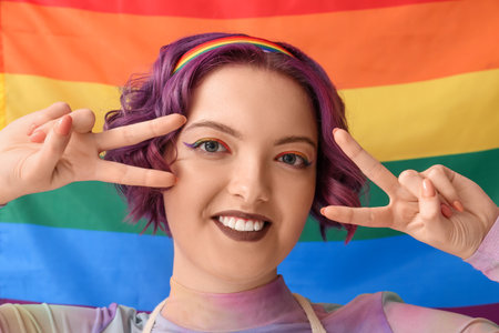 Young woman showing peace gesture against LGBT flagの写真素材