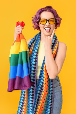 Cool young woman with LGBT flag on yellow backgroundの写真素材
