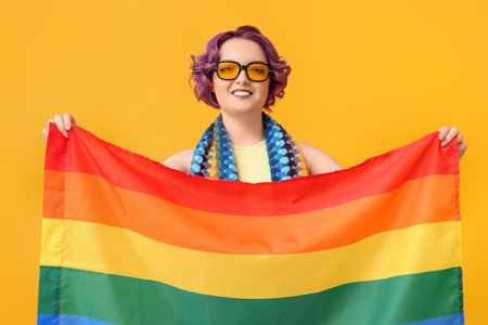 Young woman with LGBT flag on yellow backgroundの写真素材