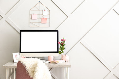 Stylish workplace with modern computer near light wall in room interiorの写真素材