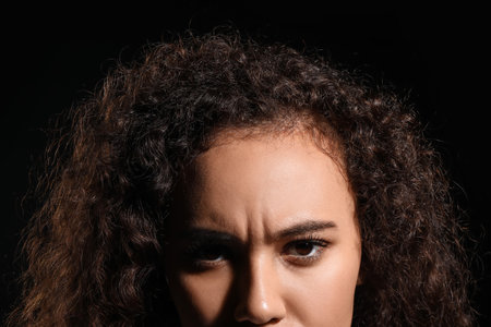 Portrait of troubled young woman on black background