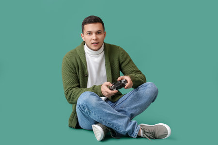 Young man playing video game on green background