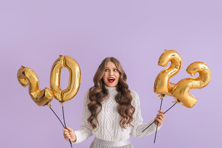 Beautiful young woman with balloons in shape of figure 2022 on color background