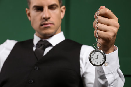 Fashionable gentleman holding vintage watch on color background, closeupの写真素材