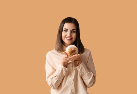 Beautiful young woman with cute guinea pig on color backgroundの写真素材
