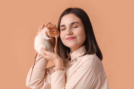 Beautiful young woman with cute guinea pig on color backgroundの写真素材
