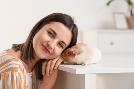 Beautiful young woman with cute guinea pig at homeの写真素材