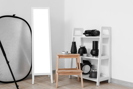 Shelving unit with lighting equipment, step stool and mirror in modern photo studioの写真素材