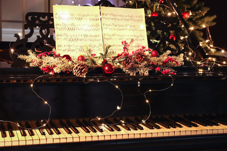 Grand piano with beautiful Christmas decor, glowing lights and note sheets in roomの写真素材