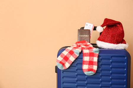 Suitcase with Santa hat, socks and documents near color wall, closeup. christmas vacation conceptの写真素材
