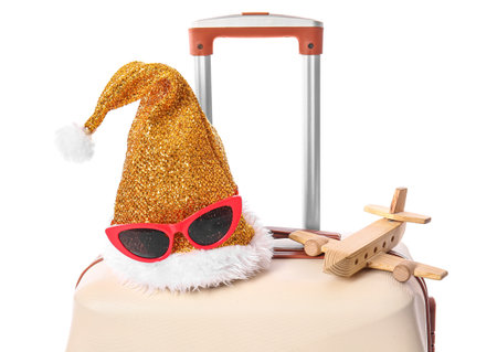 Suitcase, Santa hat, sunglasses and wooden airplane on white background, closeup. christmas vacation conceptの写真素材