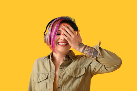 Beautiful woman with unusual hair listening to music on yellow backgroundの写真素材