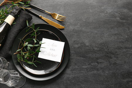 Beautiful table setting with wedding invitation on black backgroundの写真素材