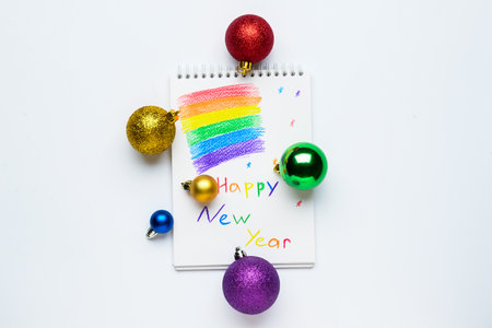 Notebook with rainbow flag and Christmas balls on white background. LGBT conceptの写真素材