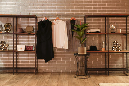 Shelving units with accessories and clothes near gray brick wallの写真素材