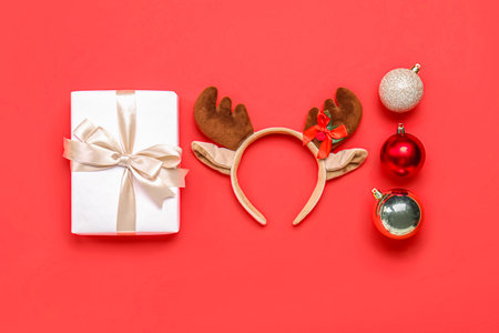 Christmas reindeer horns with balls and gift on red backgroundの写真素材