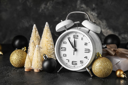 White alarm clock and beautiful Christmas decorations on dark background