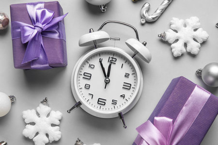 Vintage alarm clock with Christmas decor and presents on gray background