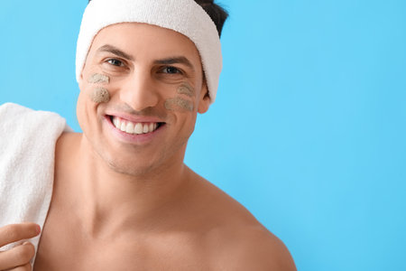 Handsome man with clay mask on blue background, closeupの写真素材