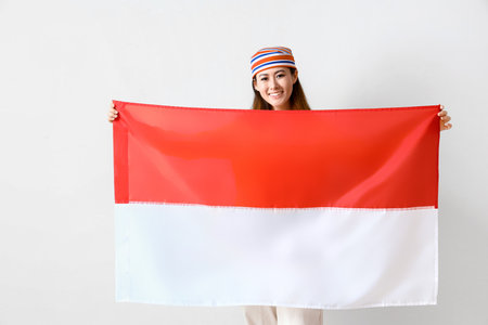 Young Asian woman with flag of Indonesia on light backgroundの写真素材