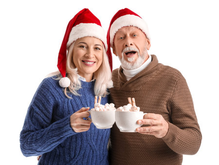 Happy mature couple in Santa hats and with hot chocolate on white backgroundの写真素材