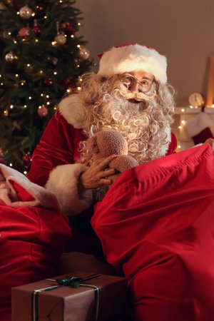 Santa Claus with toy and bag in room at Christmas night