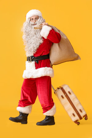 Santa Claus with sack bag and suitcase on yellow backgroundの写真素材