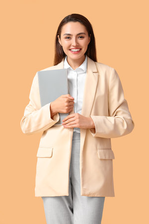 Pretty young businesswoman with folder on beige backgroundの写真素材
