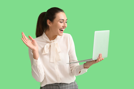 Happy young businesswoman using laptop on green backgroundの写真素材