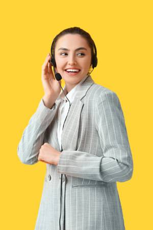 Pretty young businesswoman with headset on yellow backgroundの写真素材