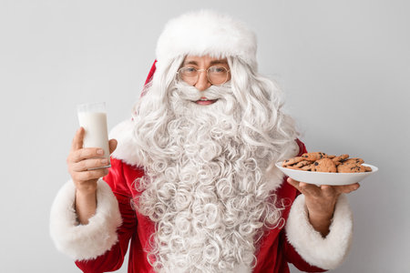 Santa Claus with tasty cookies and glass of milk on light backgroundの写真素材