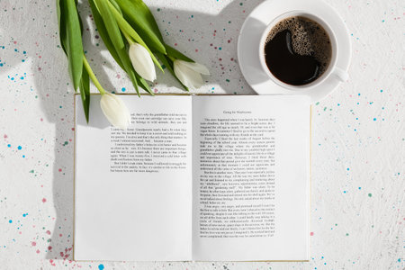 Opened book, cup of coffee and flowers on light backgroundの写真素材