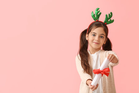 Funny little girl with reindeer horns and scroll on color backgroundの写真素材