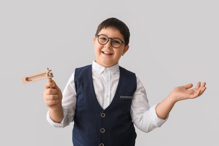 Little Jewish boy with gragger for Purim holiday on gray backgroundの写真素材