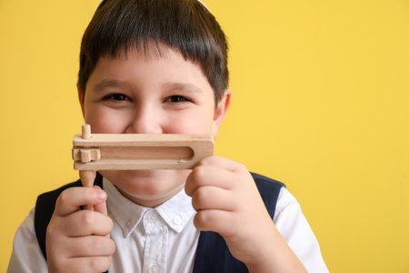 Little Jewish boy with gragger for Purim holiday on color backgroundの写真素材