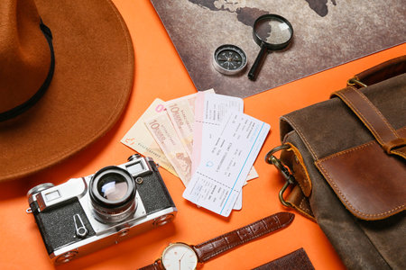 Traveling belongings with money, tickets and world map on color background