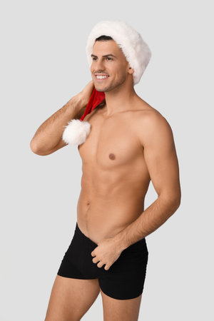 Sexy young man in Santa hat and underwear on light backgroundの写真素材
