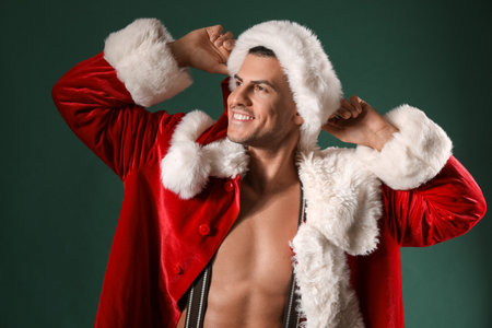 sexy young man in santa costume on dark backgroundの写真素材
