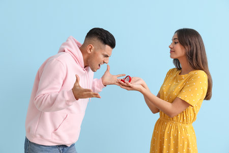 Angry young man rejecting marriage proposal on color background