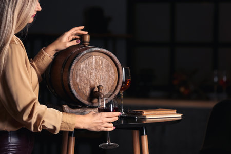 Female sommelier pouring wine from barrel into glassの写真素材