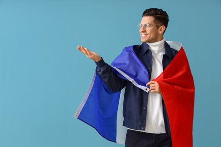 Handsome young man with flag of France showing something on blue background