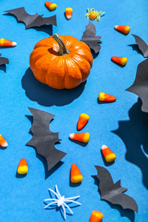 Paper bats with Halloween pumpkin and candy corns on blue backgroundの写真素材