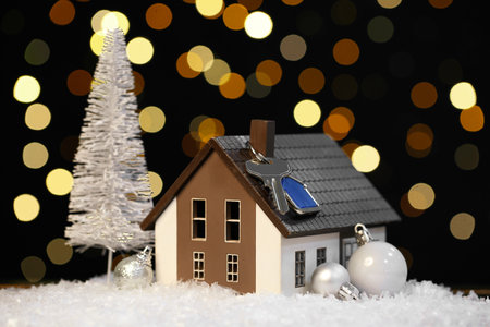 House model with key and Christmas decor on snow against blurred lightsの写真素材
