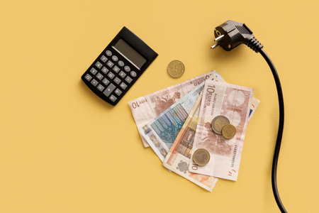 Money with plug and calculator on yellow background. heating season conceptの写真素材