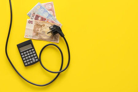 Money with plug and calculator on yellow background. heating season concept
