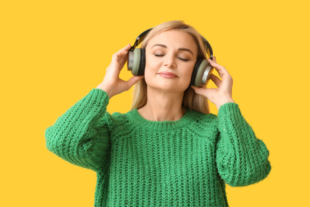 Woman with headphones listening to music on color backgroundの写真素材